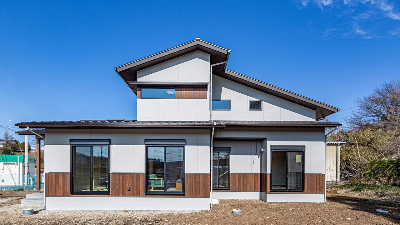 丸共建設　集い、語らい、ゆとりある暮らしの家 (大屋根の重厚感ある2階建ての住まい。外観は和風のテイストを取り入れながら外壁には腰、窓のアクセントに羽目板を使用し、懐かしさを感じさせながらモダンなテイストに仕上げました。

・内部は床に桜のフローリングを使用し、淡いピンクが空間の柔らさを感じさせ、ワントーン落としたカラーのクロスを使用し、落ち着いた空間となっています。

・玄関に入ると手洗ができ、ご家族、お子様も居住空間では清潔に生活ができます。

・土間収納には畑でとった野菜、外で使用するものを収納でき、そのままパントリー、キッチンへとつながる家事がスムーズな動線になっています。

・LDKはキッチンから全てを見通すことができ、お子様にも目が行き届く空間構成となっています。

・和室は常時オープンに使用することで、普段使い、少し横になりくつろげる場所としての使用、また友人、親御さん、お客様が見えたときは間仕切りを閉めて空間を分ける事もできます。光を通す間仕切障子によって、LDKが明るく使用できます。)