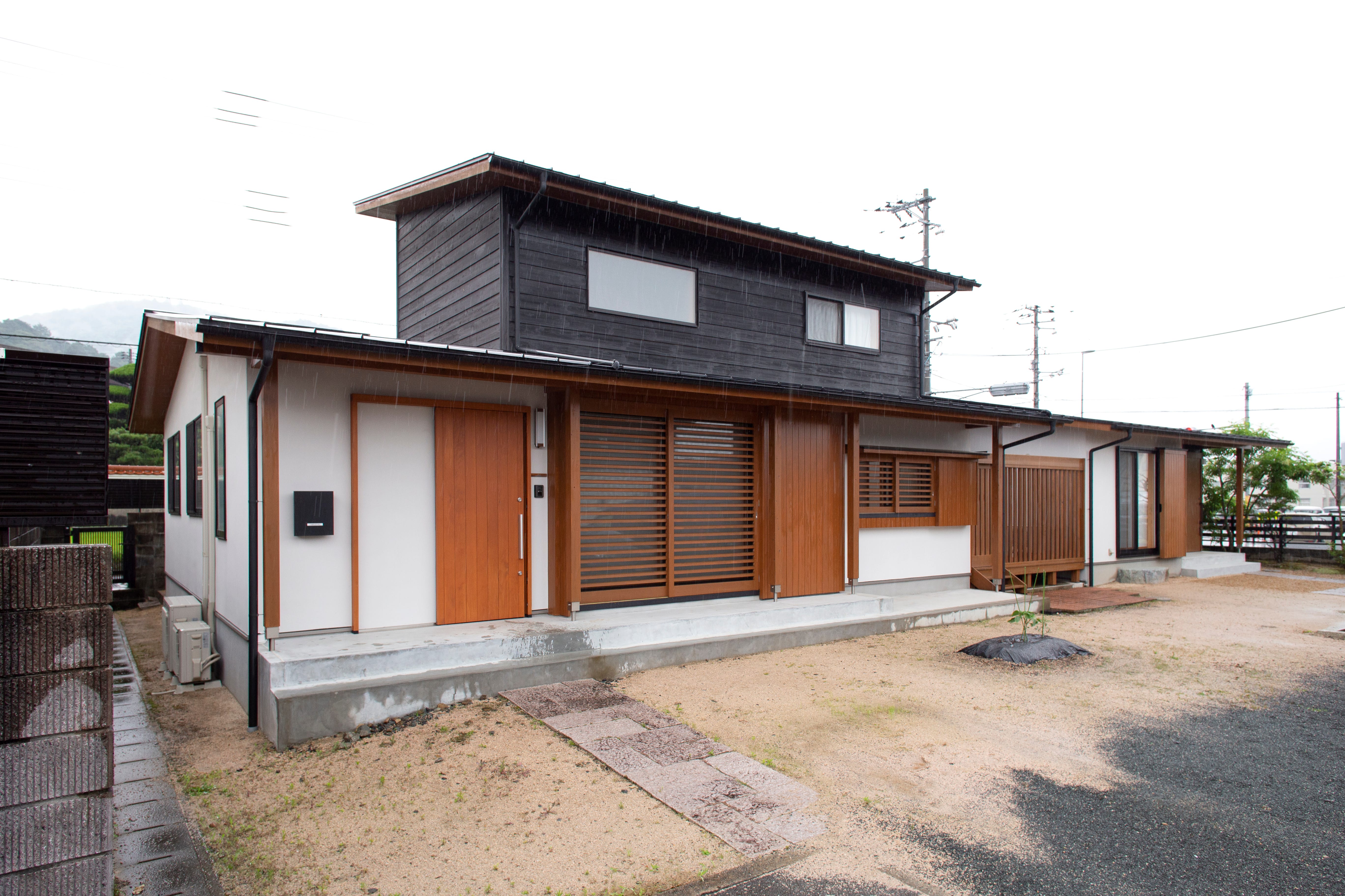 完全二世帯住宅ながら行き来もできる住まい (天井高を低くし、建物全体の高さを抑えることで落ち着いた佇まいに。
親世帯と子世帯の間に納戸とウッドデッキを挟み、各世帯にそれぞれ水回り設備を備えた完全二世帯住宅。)