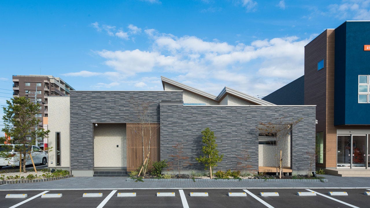 桧家住宅 佐賀平屋住宅展示場 (周囲からの目線に配慮した玄関ポーチのスリット格子と門型のゲートがモダンでスタイリッシュな外観を演出。ゲートの奥に設けられた広いウッドデッキは、玄関ポーチからもアクセスできる使いやすい空間です。
開放的な青空の下で、親戚や友人を招き大人数でバーベキューも楽しめます。リビングとホールにそれぞれ繋がる和室は、客間としての利用はもちろんリビングやウッドデッキと一体で使え家族や友人とのコミュニケーションの中心になります。また回遊できる動線の中に設けられたホールのギャラリースペースは、お気に入りの絵や季節の花などを飾れる気持ち安らぐ癒しの空間。季節や場面に合わせてアレンジし、四季を感じられるお気に入りのスペースです。その他、魅せる収納「キッチンウォールキャビ」や固定階段で上がれる大容量の「小屋裏収納」など、収納スペースもしっかり確保。佐賀展示場に詰まったたくさんのアイディア、ぜひご覧ください。)