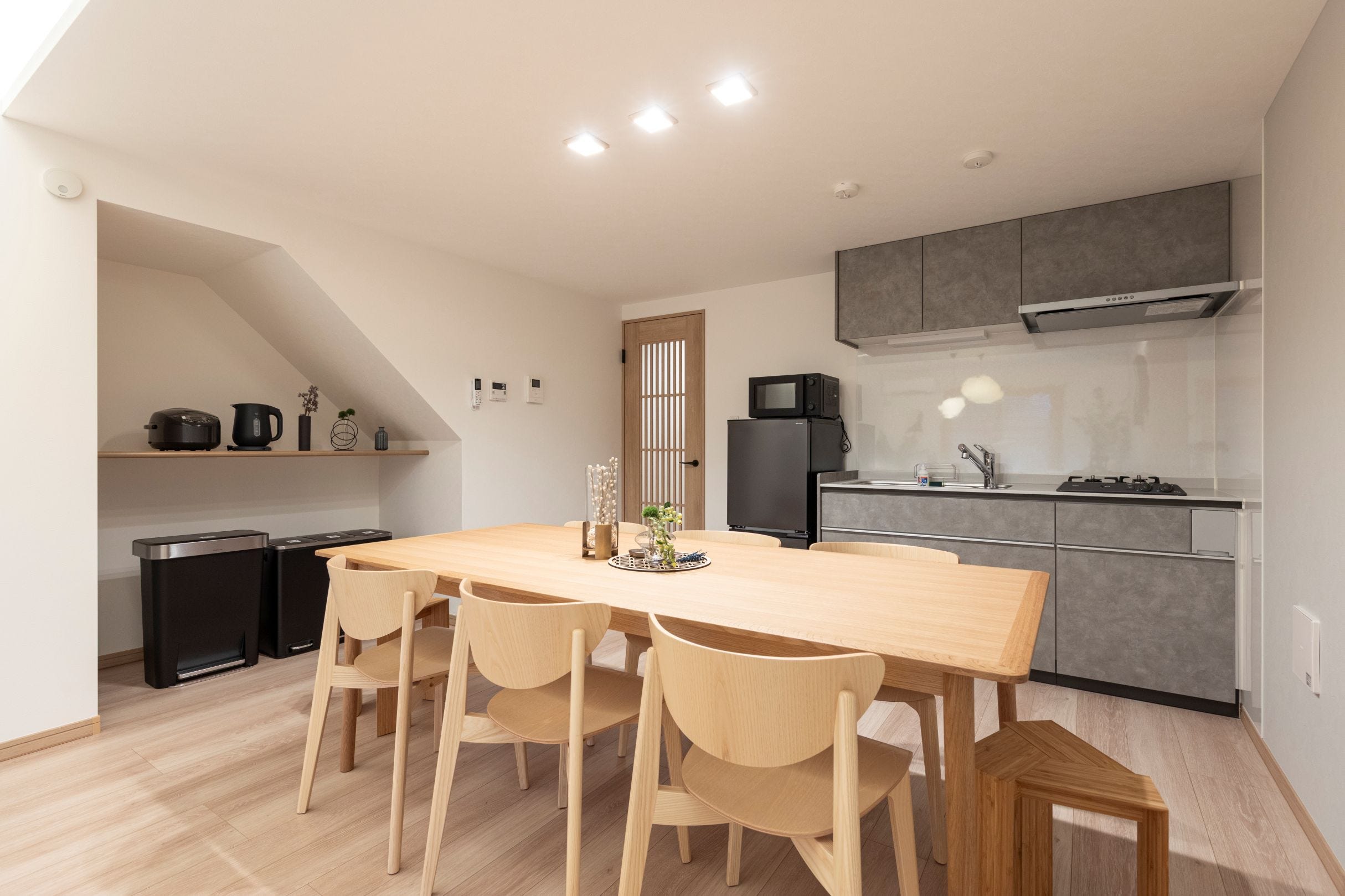 階段下のスペースを有効活用し、見た目にも美しく使い勝手の良い収納を設けました。
ダイニングは広々とした設計で、グループやファミリーでの食事もゆったり楽しめる空間に。キッチンは和テイストになじむカラーで統一し、全体を引き締める落ち着いた印象に仕上げました。