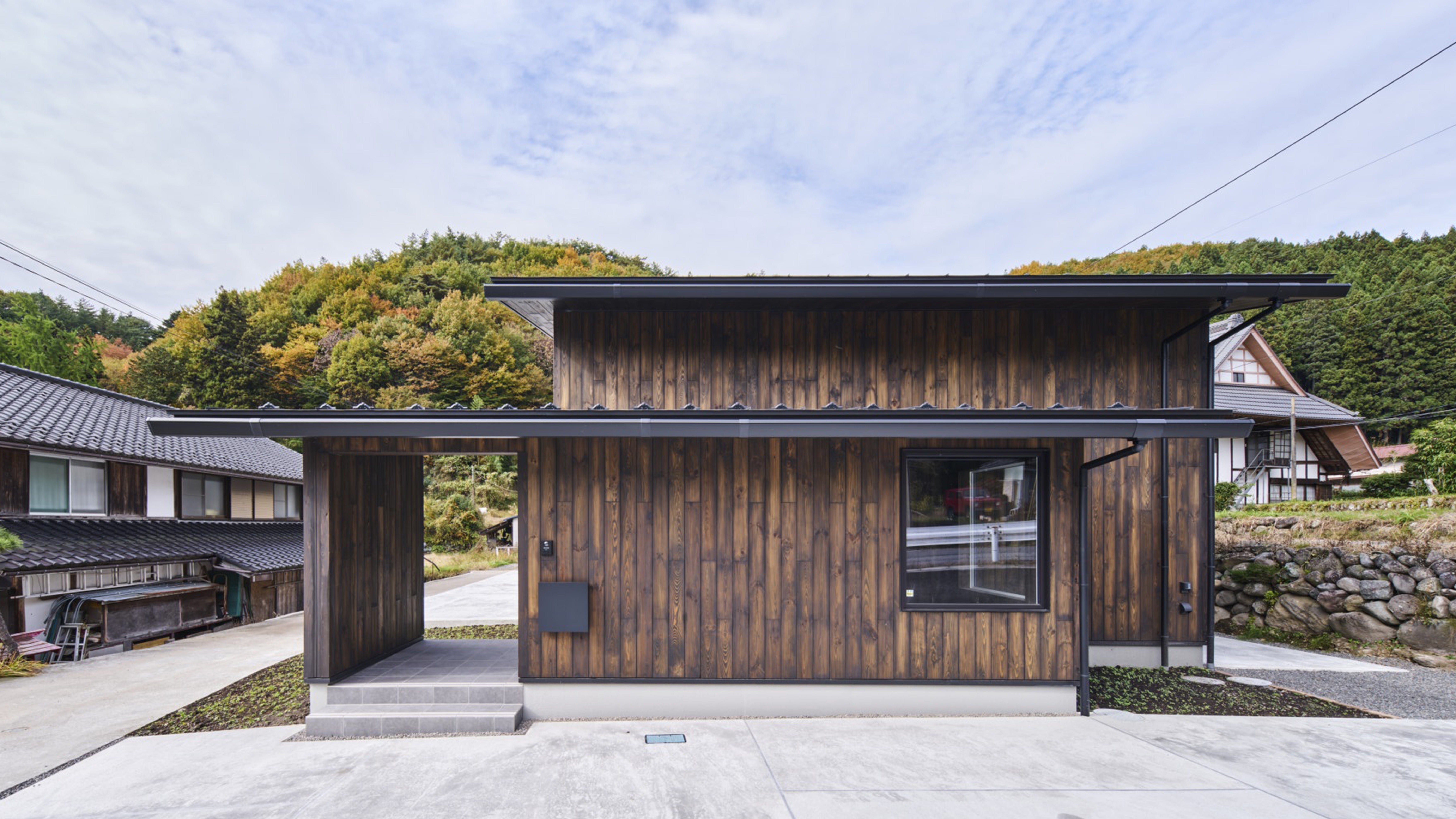 川場 ホルミシスハウス (豊かな自然に包まれた群馬県川場村に、OKUTA Family original Sanatoriumを建築致しました。四季折々の表情を楽しめる豊かな自然と、ラジウム鉱石を含んだ漆喰壁、温泉によるホルミシス効果で社員の心身のリフレッシュを目的とした施設です。 ※Sanatorium（ 療養所, 保養所, 保養院）

周囲に広がる雄大な山並みと調和するような稜線に寄り添う伸びやかな屋根形状。川場村の風景の一部となる佇まいを目指しました。外壁には、県産材を贅沢に使用した温かみのある板張りを採用し、木の質感が四季の移ろいとともに豊かな表情を生み出します。)