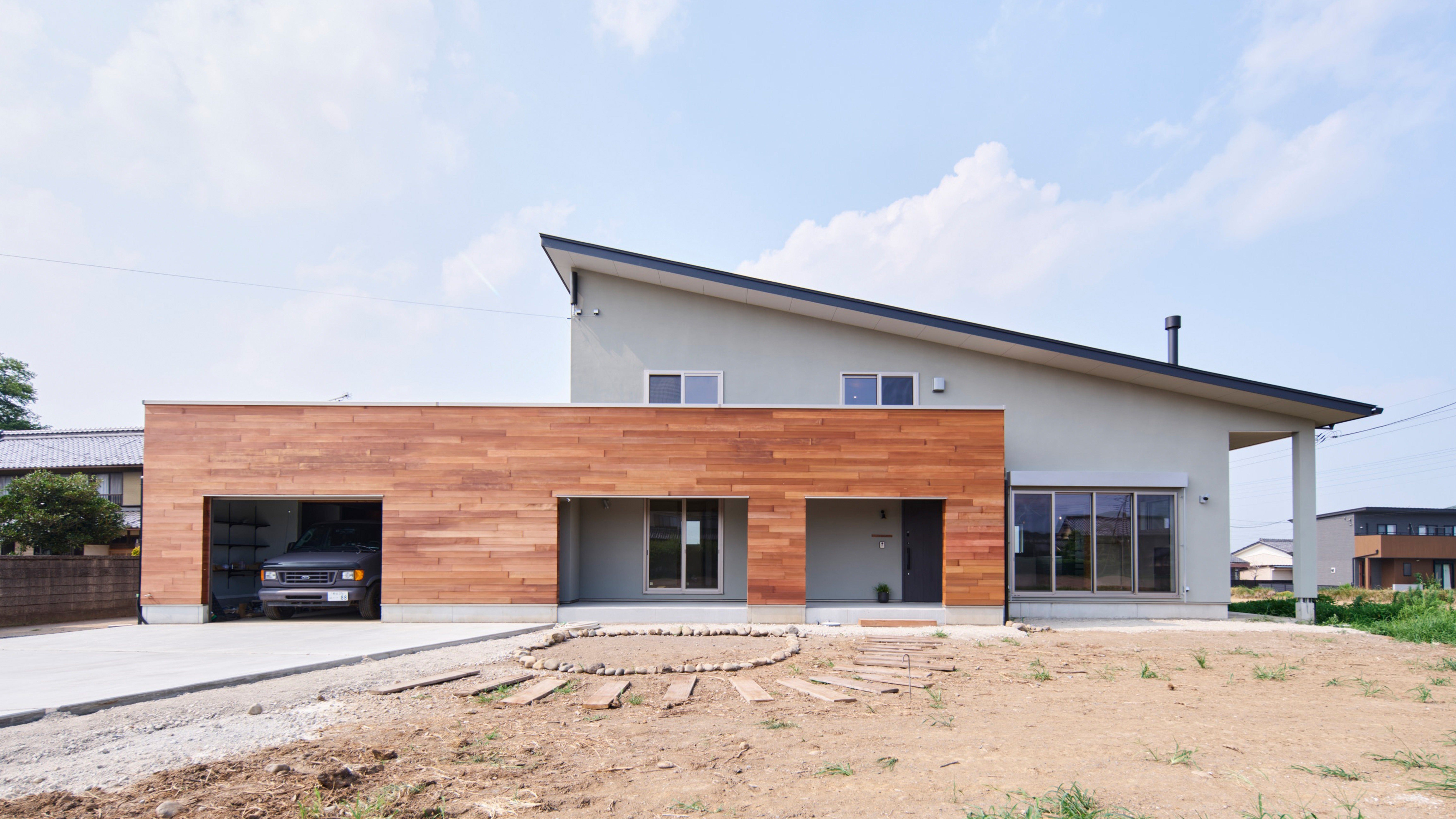 人が集い　光と景が巡る家 (田んぼが広がる自然豊かなロケーションに、自然とのつながり、そして人とのつながりを大切にした住まいが完成しました。 「人が集まる家にしたい」という想いから、全部屋から景色を堪能でき、家中を集いの場として活かせるよう家全体が繋がる設計です。 お庭ではお子様のツリーハウスや家庭菜園など、これから育まれていく楽しみも広がっています。

外壁はモルタルのリシン吹付仕上げとし、ガレージ部分にはアクセントとして板張りを採用し自然に調和する外観デザインです。 ガレージには趣味を思いっきり楽しめる工夫を詰め込みます。)